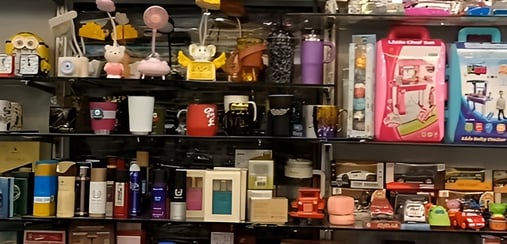 Display shelves at Royal Collection Jaipur showcasing assorted gifting items including toys, sipper bottles, mugs, skincare gift sets, miniature cars, and decorative accessories, highlighting a wide range of unique gift options