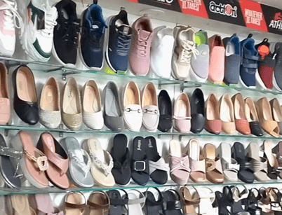 Display wall at Shoe Centre Jaipur showcasing a wide range of men’s sneakers and women’s sandals, flats and slip-ons arranged neatly on glass shelves