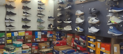 Wall display of men’s sports shoes and sneakers at Shoe Centre Jaipur, with multiple footwear boxes stacked below showcasing various brands and sizes