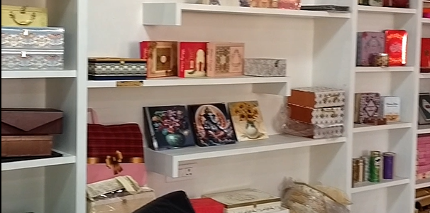 Display shelves filled with luxury sweets boxes, gift hampers, and designer invitation packaging inside a premium packaging store.