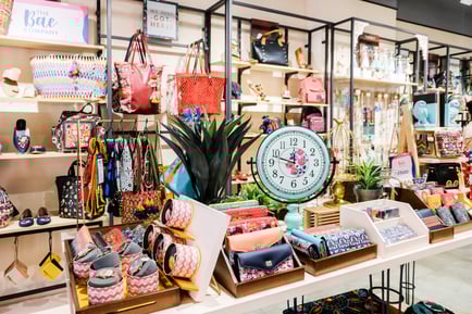 Royal Collection Jaipur store display featuring colorful handbags, wallets, wrist watches, decor items, a vintage-style floral clock, gift accessories, and handcrafted lifestyle products arranged on shelves and tables for unique gifting